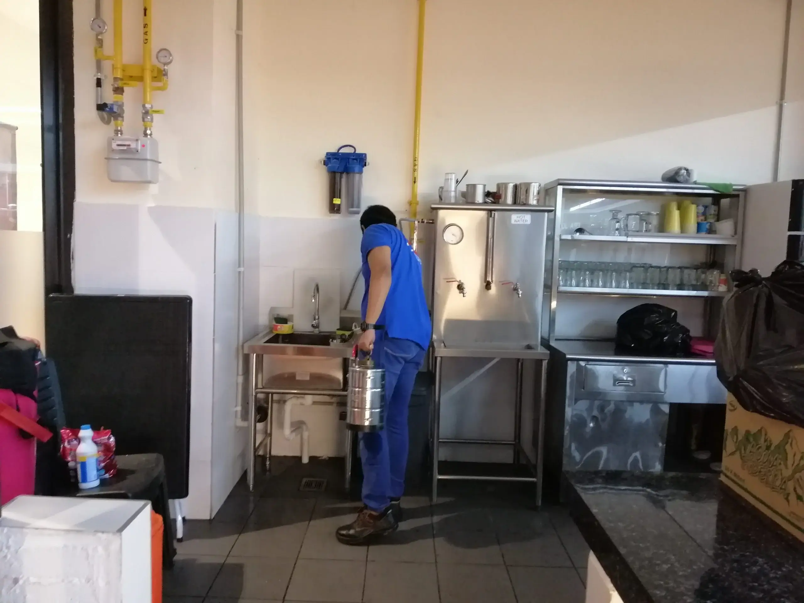 An exterminator Malaysia expert from DNI Pest Control wearing a protective suit and mask while disinfecting a residential kitchen countertop for the best pest control results.
