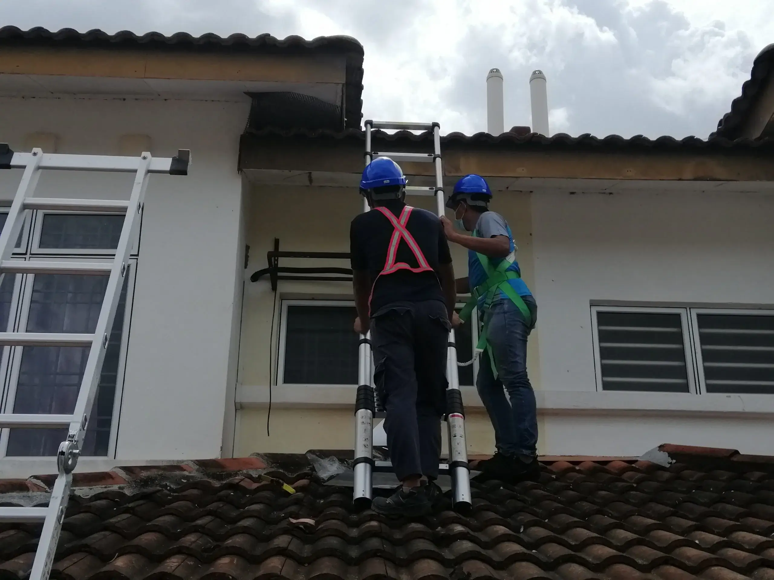 Two technicians from DNI Pest Control using safety harnesses and ladders to inspect a roof, showing why they are the most thorough exterminator Malaysia has for residential properties.